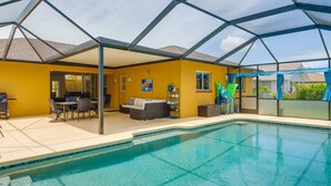 A covered outdoor swimming pool area with a patio, seating, and a barbecue grill. - Heated Pool: Pet-friendly Home in Cape Coral (Cape Coral)