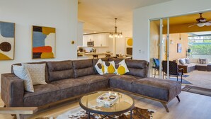 A modern living room with a sectional sofa, a glass coffee table, and a cowhide rug. - Heated Pool: Pet-friendly Home in Cape Coral (Cape Coral)