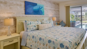 A bedroom with a bed, nightstands, a lamp, a painting, and a view of the outdoors. - Cape Coral Home w/ Private Heated Pool & Lanai! (Cape Coral)