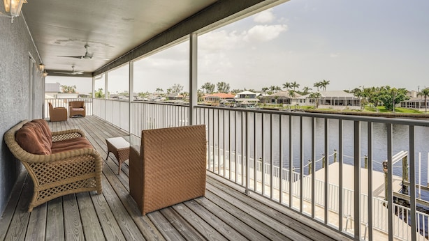 A balcony with wicker furniture, a ceiling fan, and a view of a marina. - Waterfront Retreat w/ Pool on Caloosahatchee River (Cape Coral)