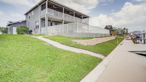 A two-story building with a balcony, a paved walkway, and a grassy area. - Waterfront Retreat w/ Pool on Caloosahatchee River (Cape Coral)