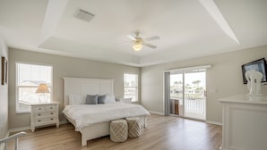 A spacious bedroom with a large bed, a ceiling fan, and a view of the outdoors through a sliding glass door. - Waterfront Retreat w/ Pool on Caloosahatchee River (Cape Coral)