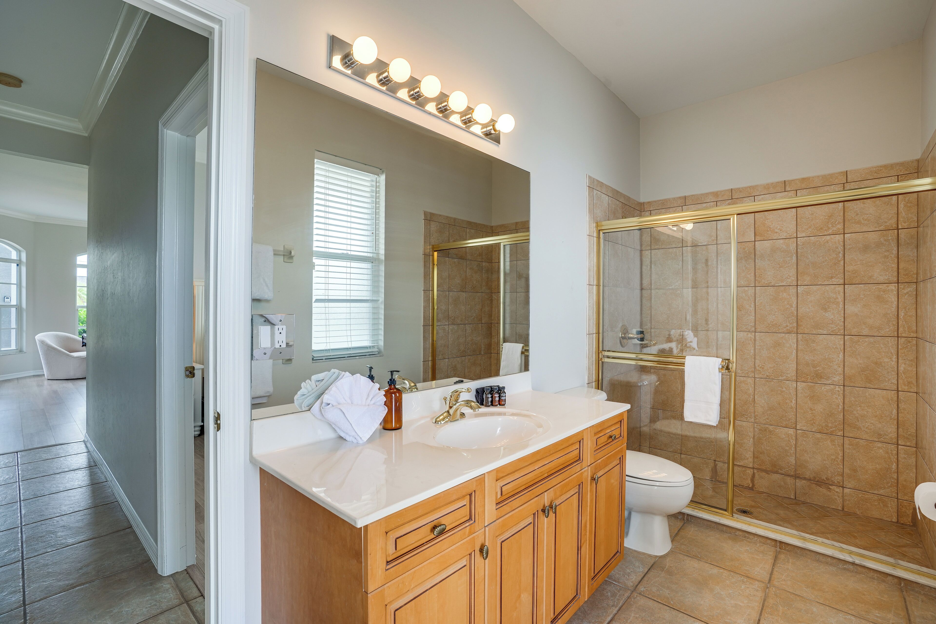 A modern bathroom with a large mirror, vanity, and a walk-in shower.