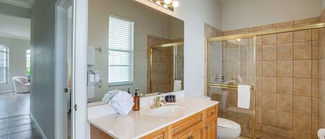A modern bathroom with a large mirror, vanity, and a walk-in shower.