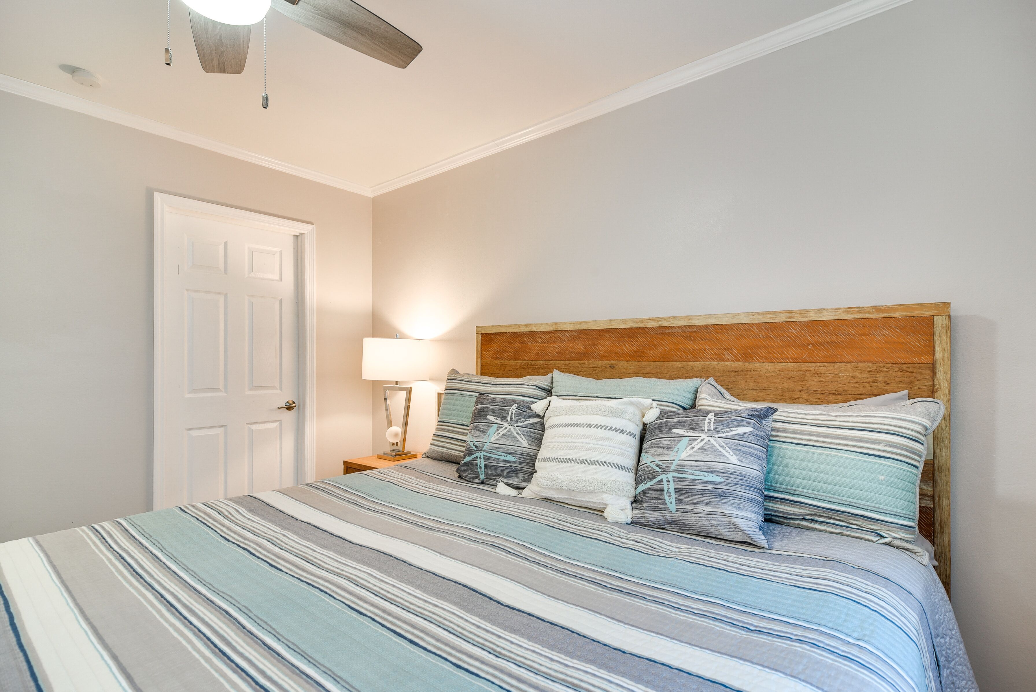 A bedroom with a bed, a nightstand, a lamp, and a ceiling fan.