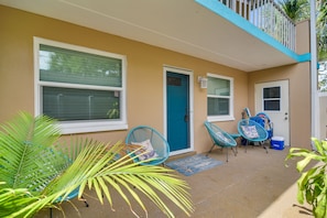 A covered outdoor area with a blue door, two blue chairs, and a small table. - Indian Rocks Beach Retreat: Walk to Beaches! (Indian Rocks Beach)