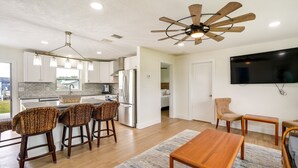 Une cuisine moderne avec un coin repas, un ventilateur de plafond en bois et un téléviseur à écran plat.