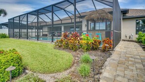 Ein modernes Haus mit einer großen Glaskonstruktion, einem Swimmingpool und einem gepflegten Garten.