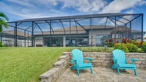 Ein modernes Haus mit einer überdachten Terrasse, auf der zwei Adirondack-Stühle stehen.