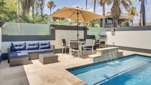 A poolside area with a sofa, chairs, a table, and a grill. - South Padre Island Retreat: Private Pool! (South Padre Island)