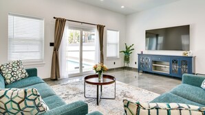 A spacious living room with teal sofas, a round coffee table, and a large flat-screen TV. - South Padre Island Retreat: Private Pool! (South Padre Island)