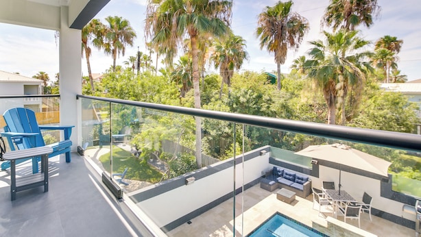 A balcony with a glass railing, blue Adirondack chairs, a pool table, and a sofa. - South Padre Island Retreat: Private Pool! (South Padre Island)