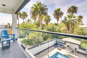 A balcony with a glass railing, blue Adirondack chairs, a pool table, and a sofa. - South Padre Island Retreat: Private Pool! (South Padre Island)