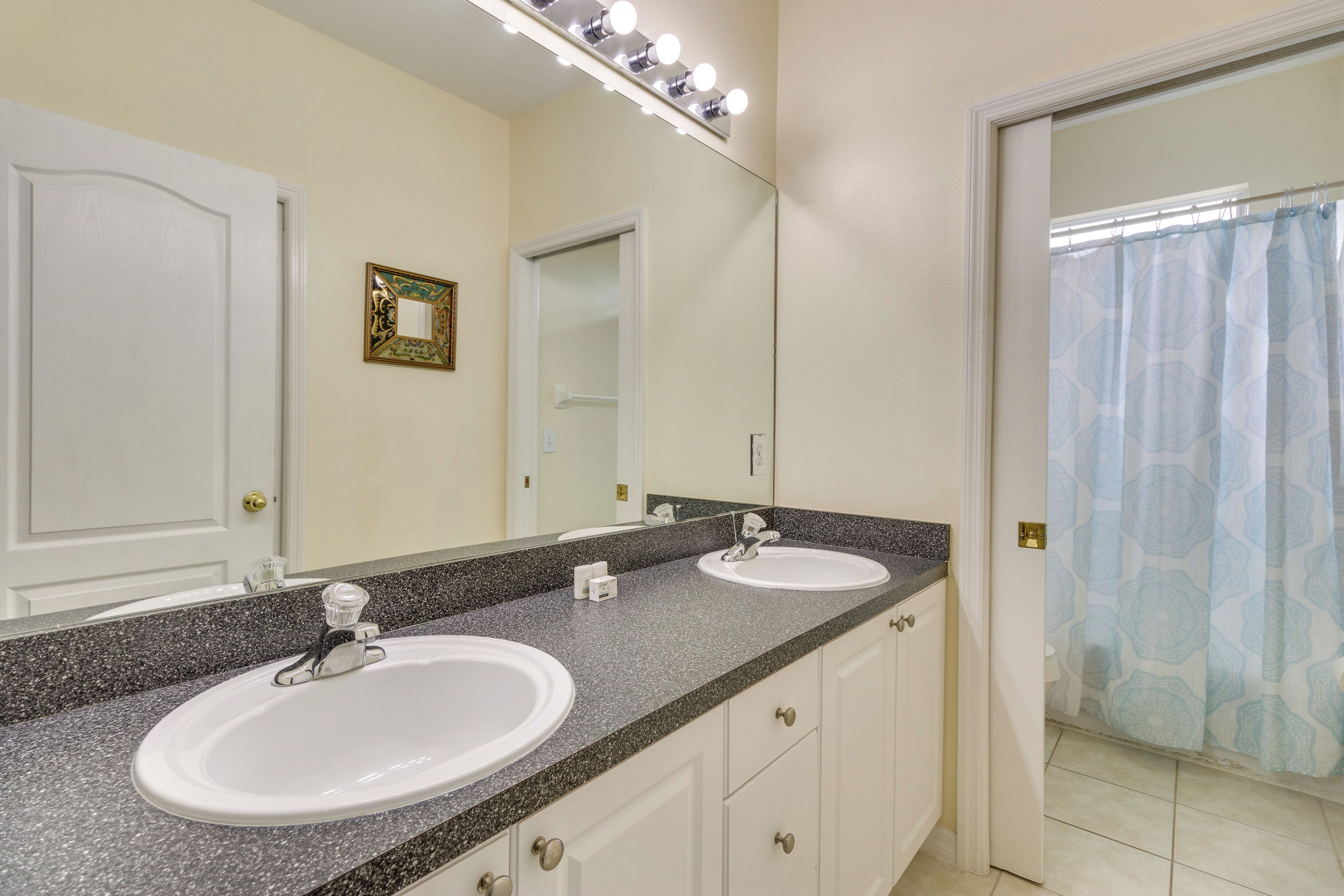 A bathroom with two sinks, a large mirror, and a shower curtain.