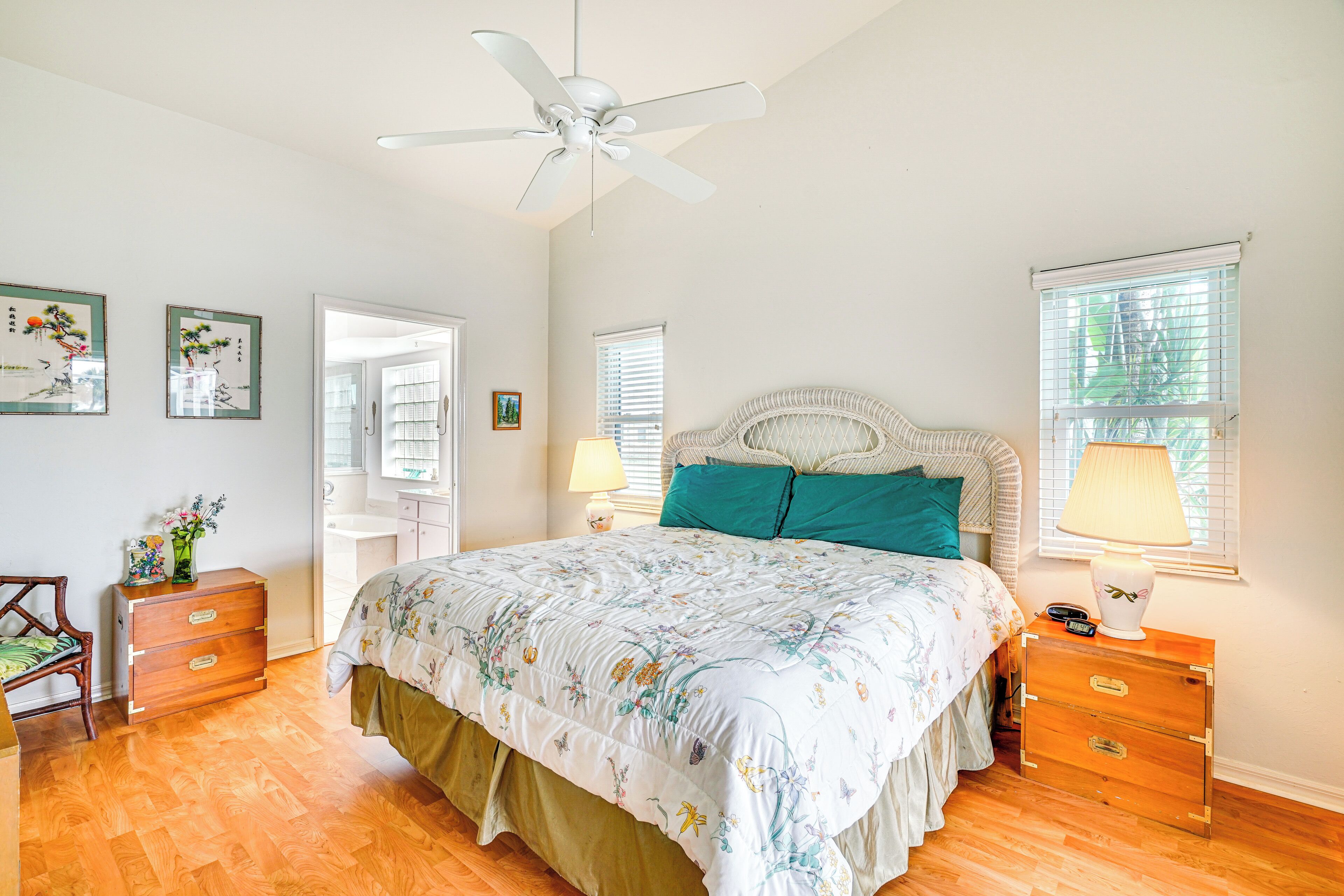 A bedroom with a bed, wooden dresser, nightstand, and ceiling fan.