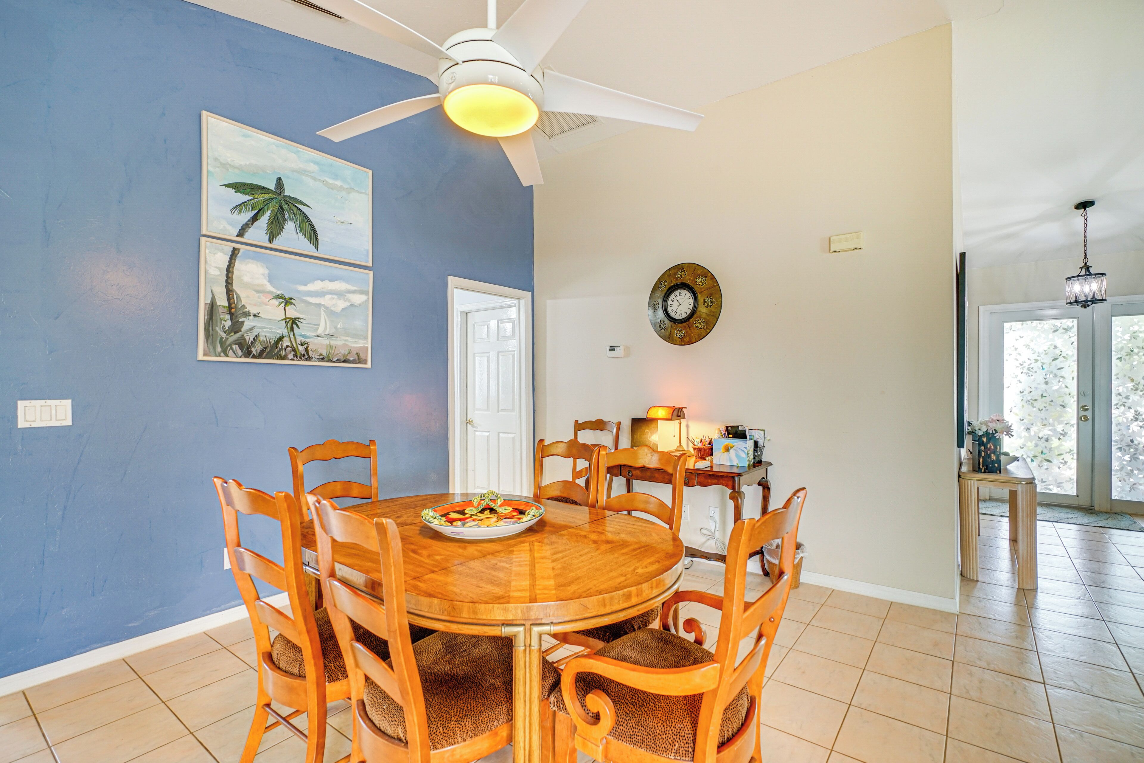 A dining area with a round wooden table, six chairs, and a ceiling fan.