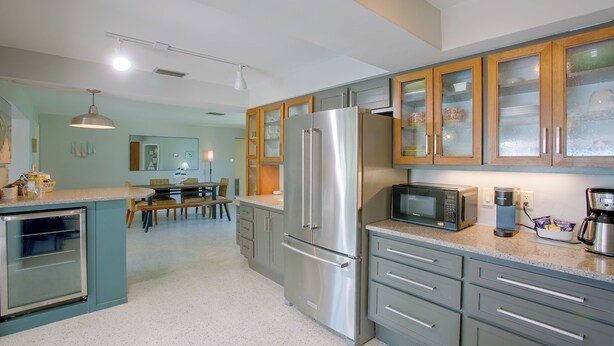 A modern kitchen with stainless steel appliances, wooden cabinets, and a dining area with a table and chairs.