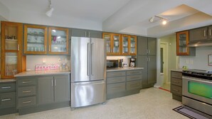 Eine moderne Küche mit grauen Schränken, einem Edelstahlkühlschrank und einem Einbauofen.