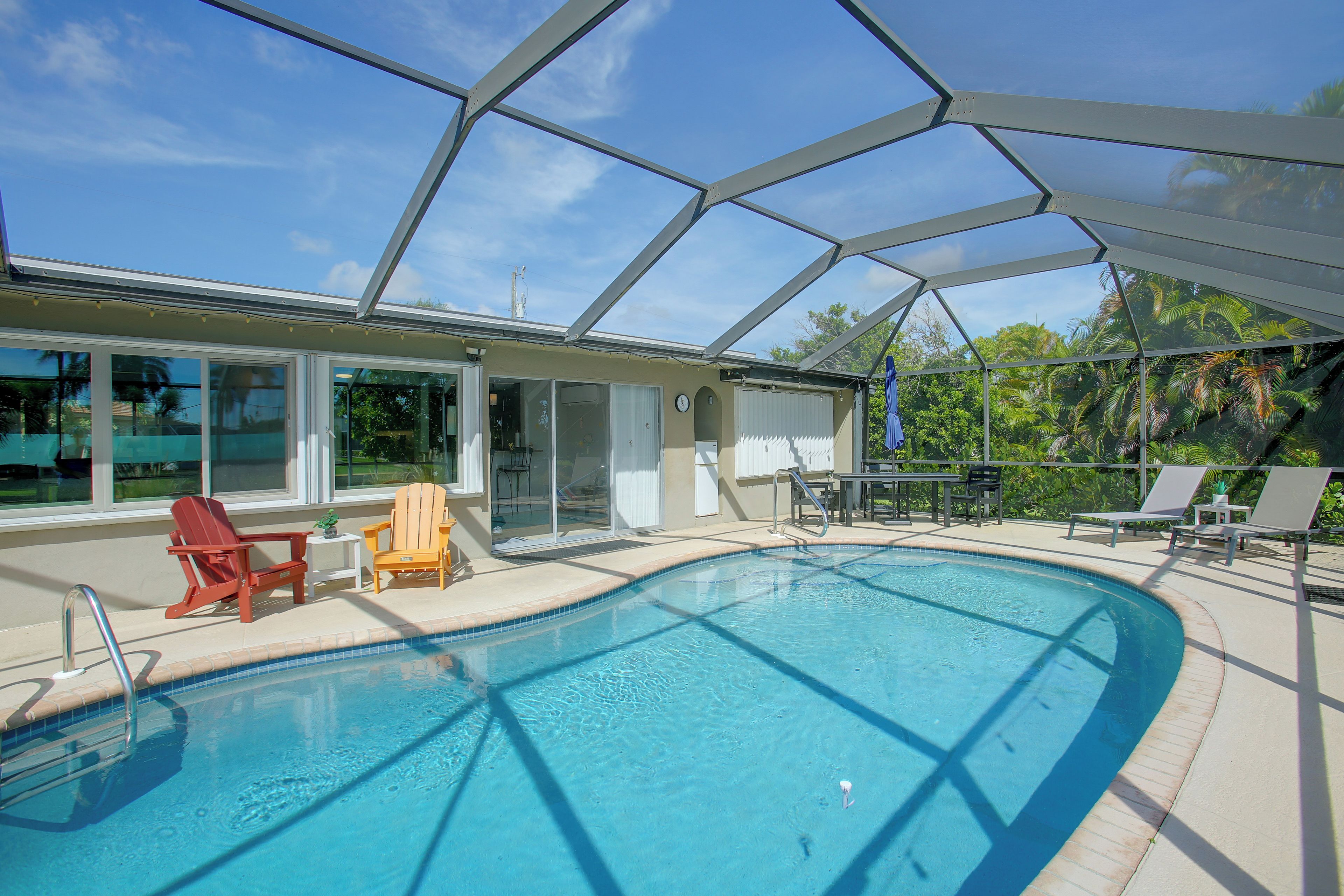 A swimming pool with a glass enclosure, surrounded by lounge chairs and a patio area.