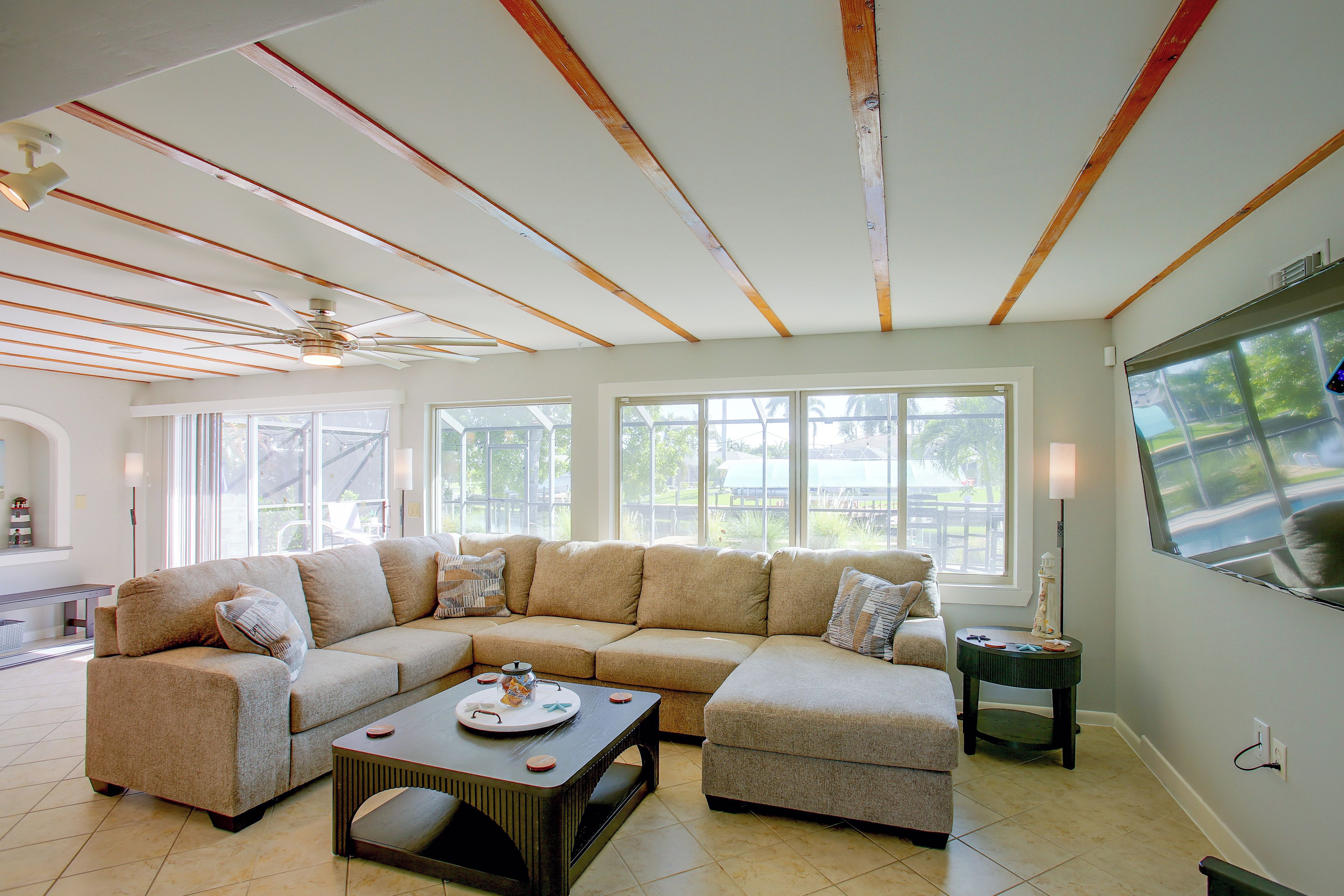 A living room with a sectional sofa, a coffee table, and a ceiling fan.
