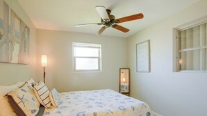 A bedroom with a bed, a ceiling fan, a window, and a door.