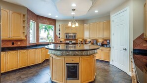 A spacious kitchen with a central island, wooden cabinets, a built-in microwave, and a stainless steel oven.