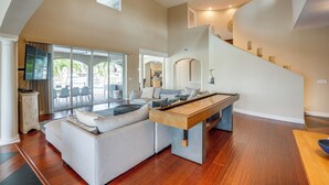 A spacious living area with a pool table, a sofa, and a staircase leading to an upper level.