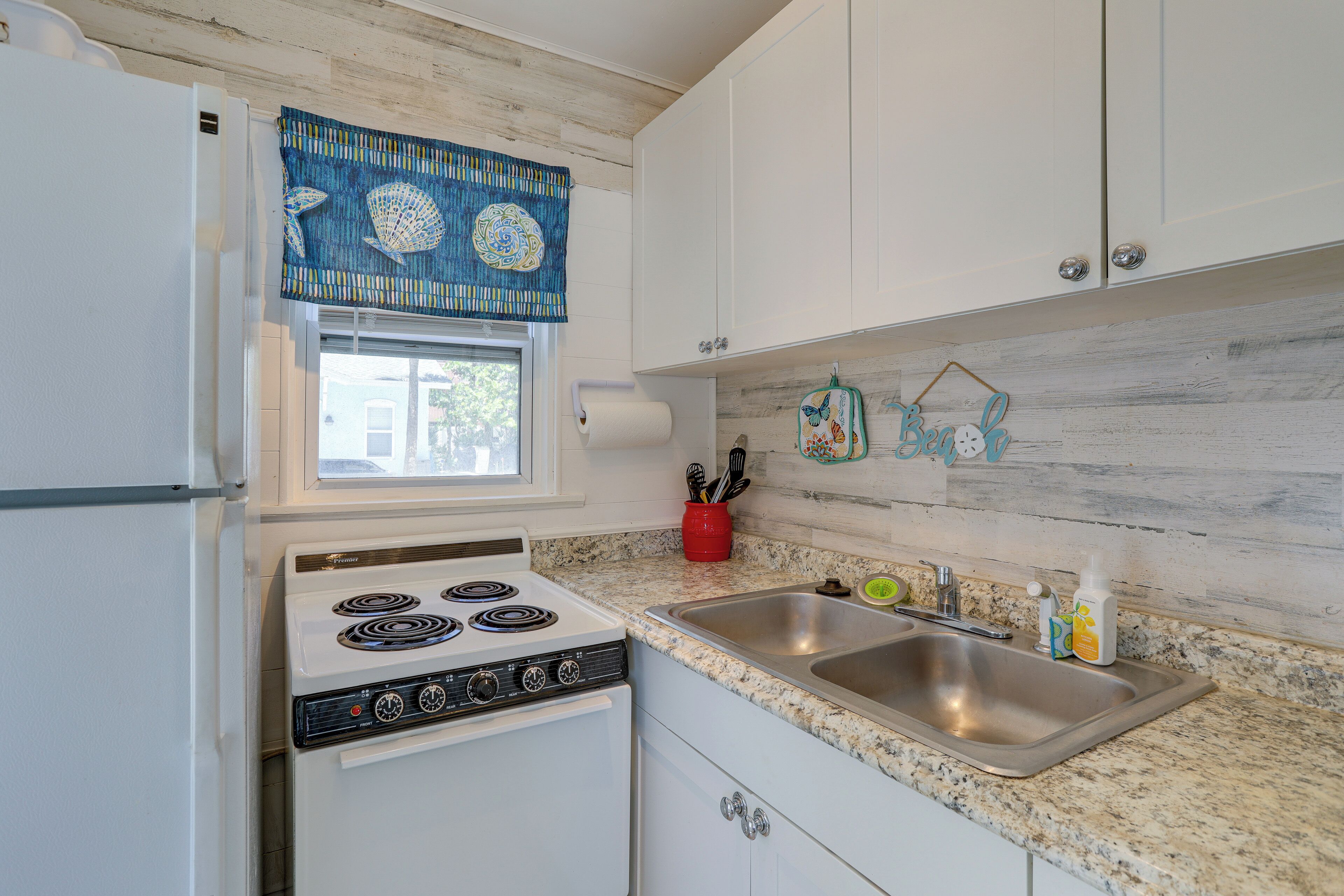 A kitchen with a white refrigerator, a stove, a sink, and cabinets.