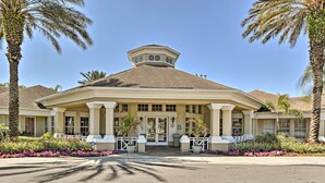 A hotel with a central entrance, palm trees, and a covered patio area.