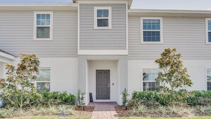 A two-story building with a gray exterior, a central entrance with a dark door, and a small porch area. - Davenport Home ~ 15 Mi to Disney World! (Davenport)