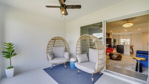 A balcony with two wicker chairs, a potted plant, and a ceiling fan. - Davenport Home ~ 15 Mi to Disney World! (Davenport)
