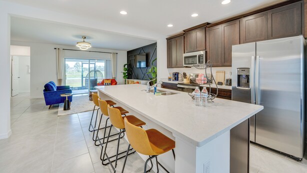 A modern kitchen with a large island, bar stools, and stainless steel appliances. - Davenport Home ~ 15 Mi to Disney World! (Davenport)