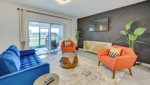 A modern living room with a blue sofa, an orange armchair, and a geometric coffee table. - Davenport Home ~ 15 Mi to Disney World! (Davenport)