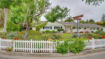 Surrounded by lush greenery and mature trees, this charming home features a traditional gabled roof and a welcoming front porch.