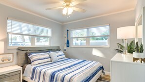 A bedroom with a bed, bedside tables, a ceiling fan, and windows. - Indian Rocks Beach Escape: Beach Gear, Near Ocean! (Indian Rocks Beach)