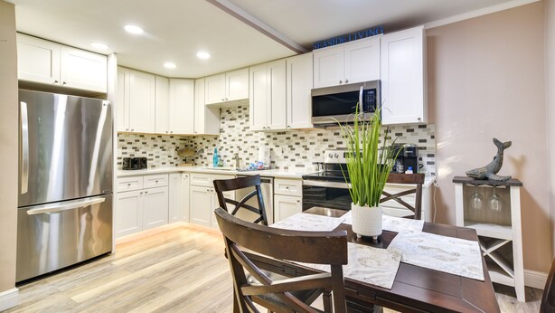 A modern kitchen with white cabinets, stainless steel appliances, and a tiled backsplash. - Indian Rocks Beach Escape: Beach Gear, Near Ocean! (Indian Rocks Beach)