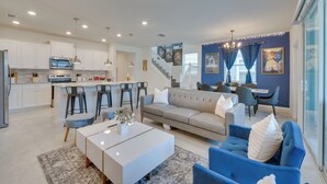 A modern kitchen with white cabinets, a central island, and bar stools. - Pool, Games & Disney Magic! Epic Family Oasis (Davenport)