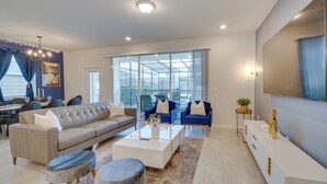 A modern living room with a sofa, coffee table, and chairs, large windows, and a dining area. - Pool, Games & Disney Magic! Epic Family Oasis (Davenport)