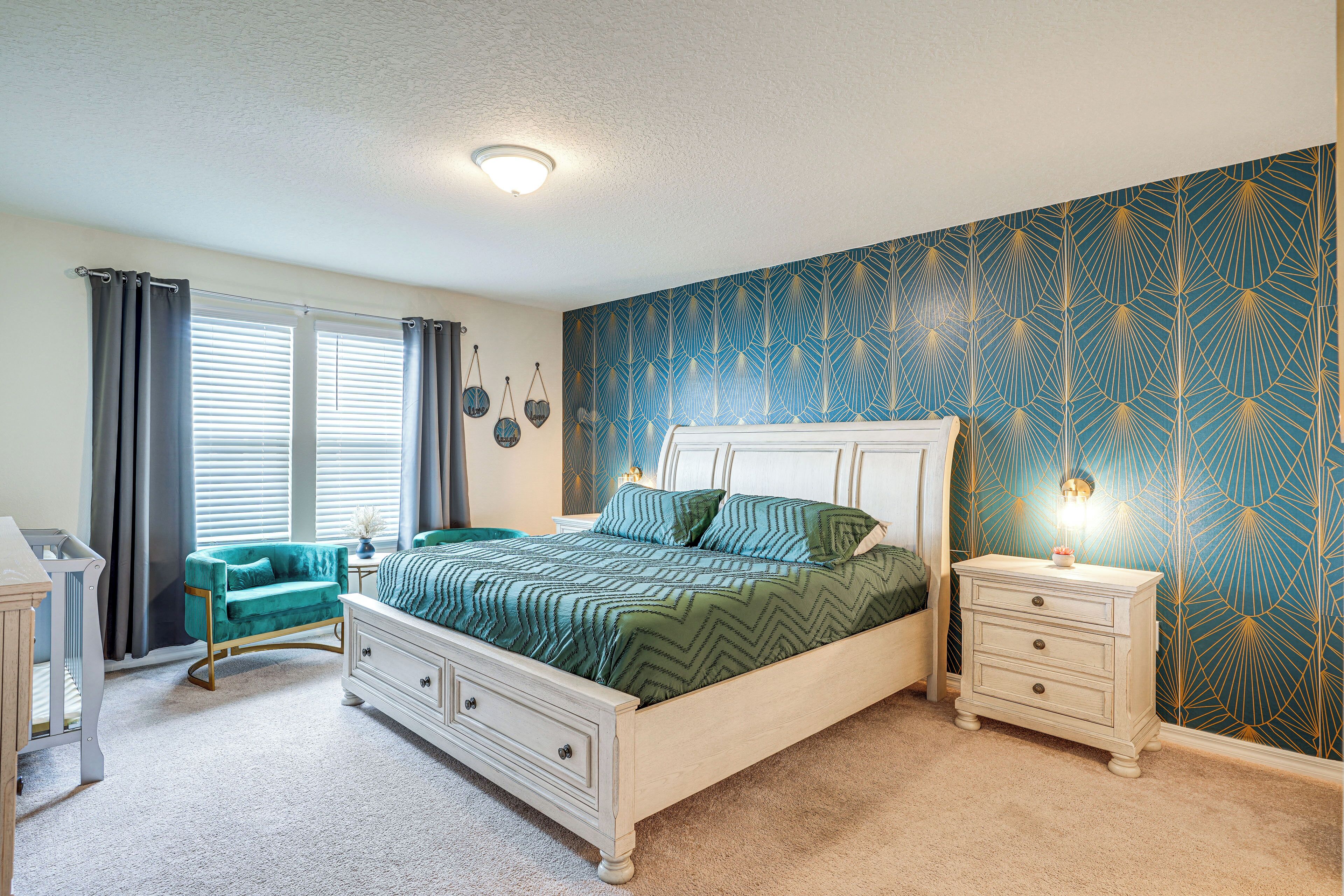 A bedroom with a bed, a nightstand, a dresser, a chair, and a crib.