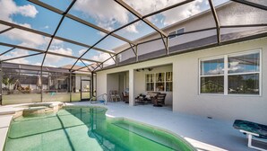 An indoor swimming pool with a glass ceiling, surrounded by a patio area with chairs and a bench. - Davenport Family Home w/ Private Lanai & Game Room (Davenport)
