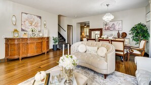 A spacious living room with a large sofa, a dining table, and a chandelier. - Davenport Family Home w/ Private Lanai & Game Room (Davenport)