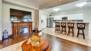 A spacious kitchen with white cabinets, a stainless steel refrigerator, and a bar area with stools. - Davenport Family Home w/ Private Lanai & Game Room (Davenport)