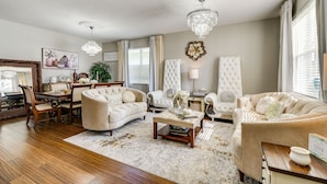 A spacious living room with a large chandelier, plush sofas, and a dining area with wooden furniture. - Davenport Family Home w/ Private Lanai & Game Room (Davenport)