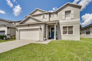 A two-story house with a garage, a front porch with a potted plant, and a well-maintained lawn.