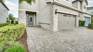 A modern two-story house with a stone facade, a grey garage door, and a paved driveway. - Spacious Kissimmee Escape, Close to Disney World! (Kissimmee)
