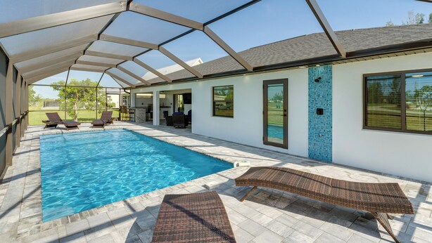 A covered swimming pool area with lounge chairs and a patio. - Private Pool & Grill: Cape Coral Vacation Rental! (Cape Coral)