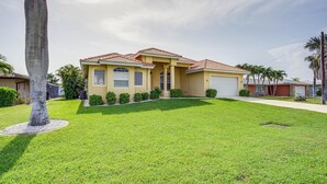 A two-story house with a red-tiled roof, a front yard with a palm tree, and a well-maintained lawn.