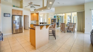 A spacious kitchen with a central island, a refrigerator, and a ceiling fan.