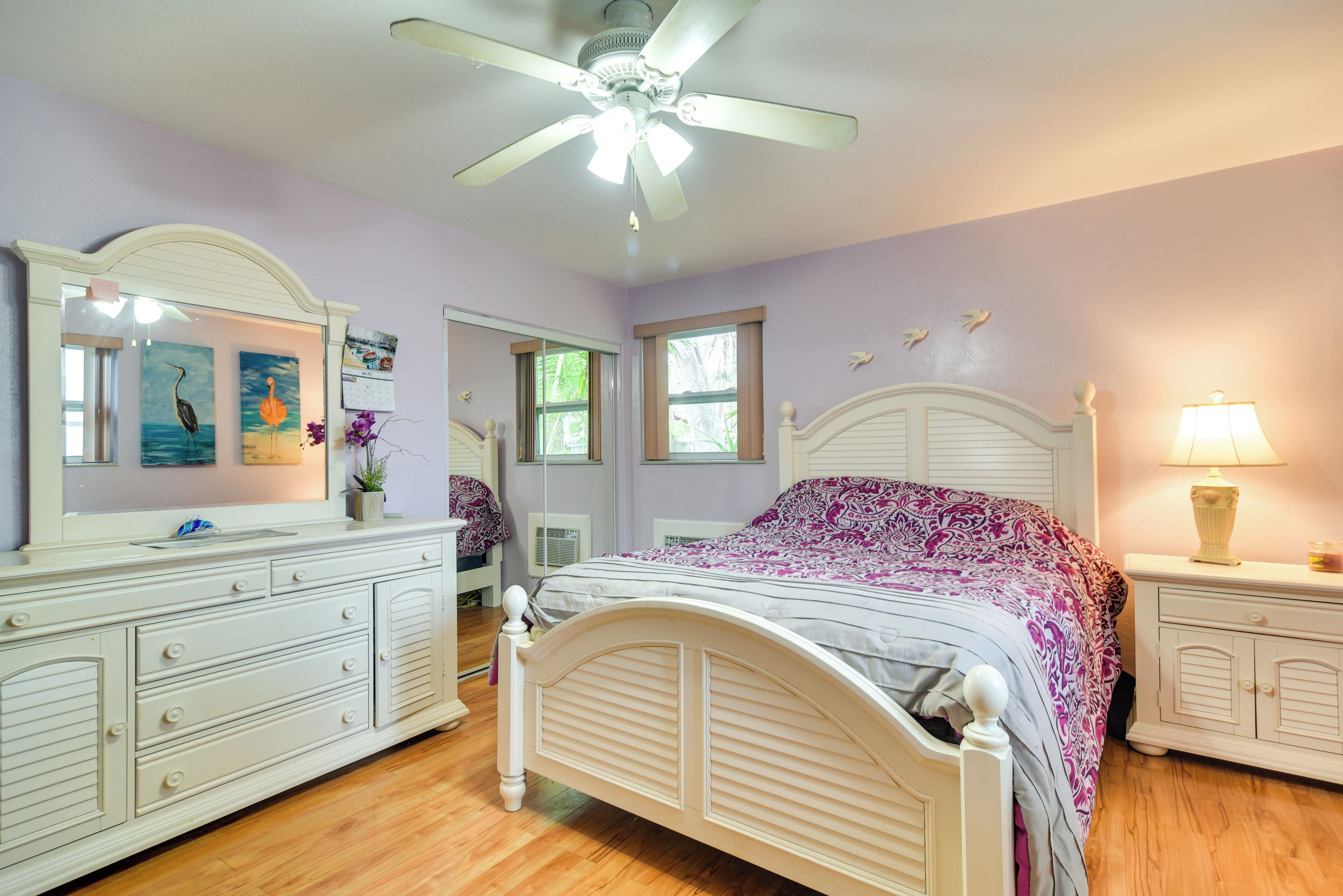 Ein Schlafzimmer mit Bett, Kommode, Schminktisch und Deckenventilator.