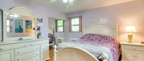 Ein Schlafzimmer mit Bett, Kommode, Schminktisch und Deckenventilator.